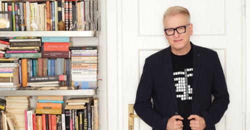 Pisarz Mariusz Szczygieł w mieszkaniu na tle regału fot. Michał Mutor